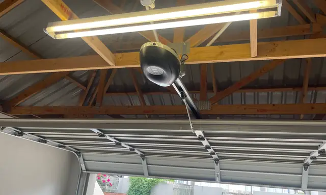 Automated sectional garage door with the motor mounted to the roof trusses